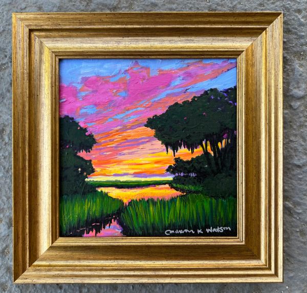 Framed painting of a vibrant sunset over marshland with silhouetted trees.