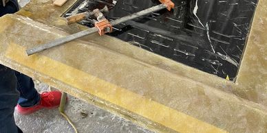 Person wearing orange gloves clamps a wooden strip on a fiberglass project.