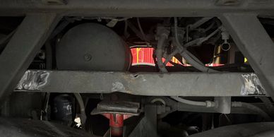 Close-up of mechanical parts and pipes under a vehicle or industrial machine.