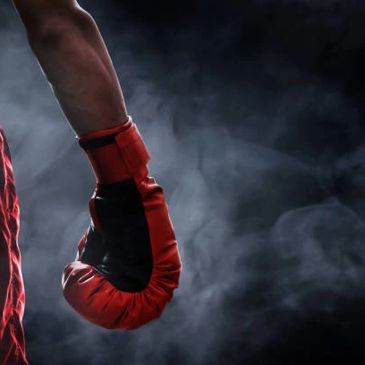 Poing levé avec un gant de boxe rouge dans une ambiance sombre.