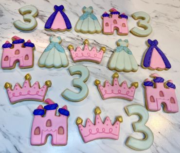 Princess-themed decorated cookies with the number 3, castles, crowns, and dresses.