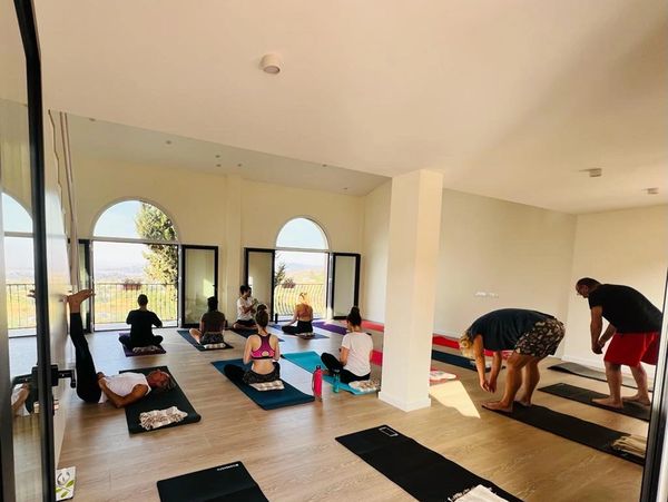 Group yoga session in a spacious, sunlit room with large windows.