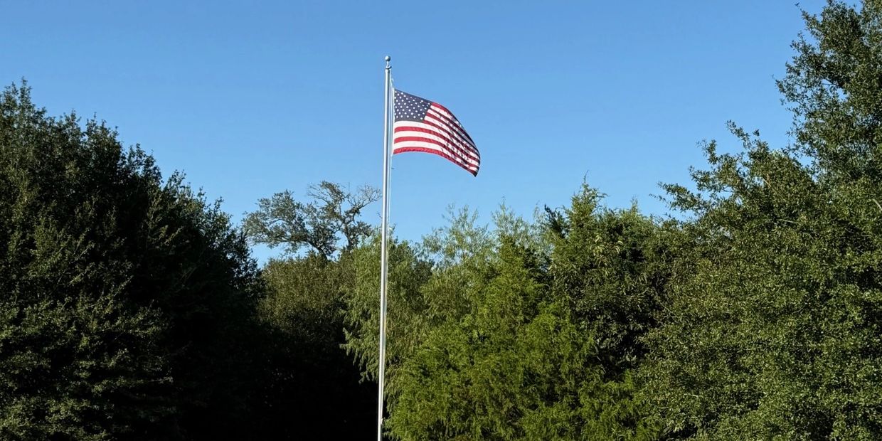 American flag waving on a tall flagpole against a clear blue sky.