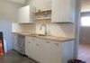 Kitchen sink area with butcher block counter and shelving. Stainless steel sink and appliances.