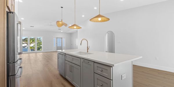 Modern kitchen with white island and wooden floor.