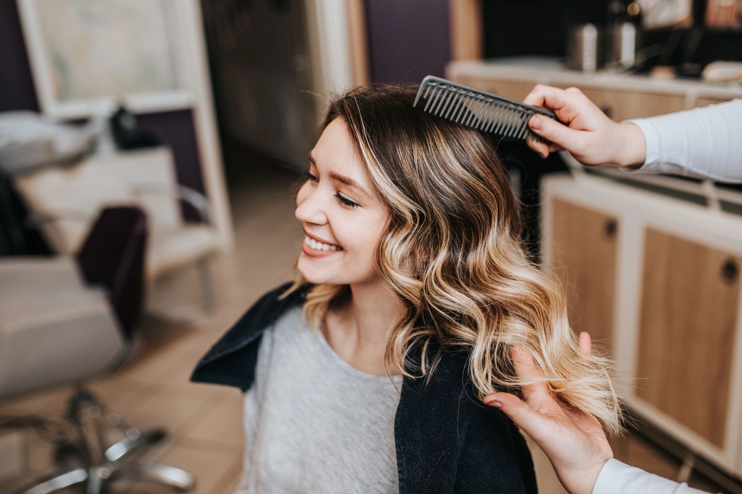 Beautiful hairstyle of young woman after hair dyeing and making highlights in hair salon.