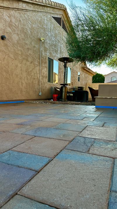 Backyard patio with stone tiles, outdoor furniture, and a heater under a tree.
