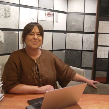 Woman sitting at desk with laptop, smiling.