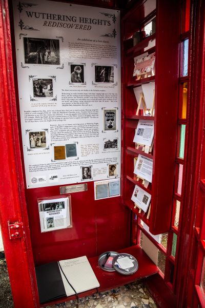 A red phone booth converted into a Wuthering Heights exhibit with photos and texts.