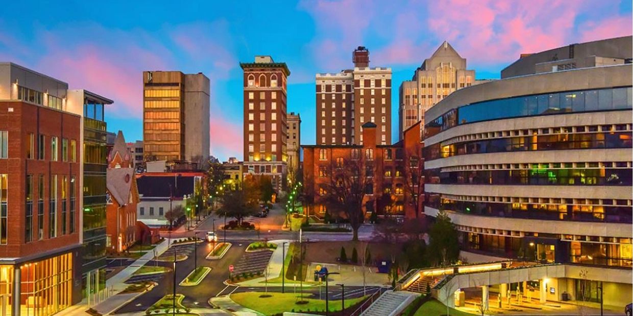 City skyline at dusk with colorful sky and illuminated buildings.