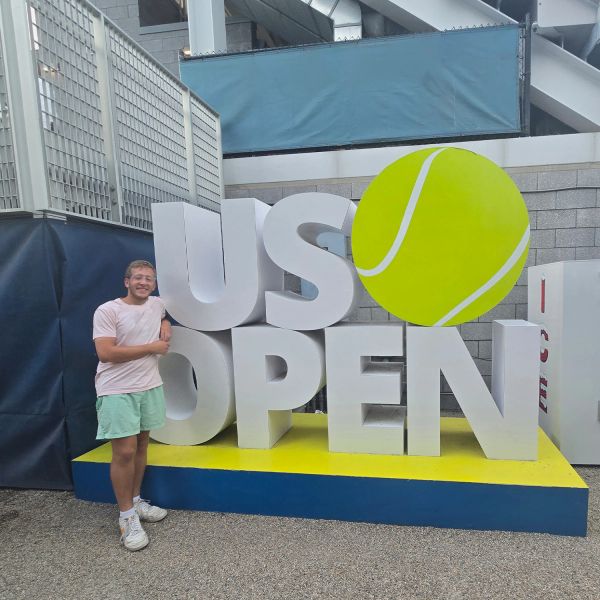 Person posing next to US Open sign.