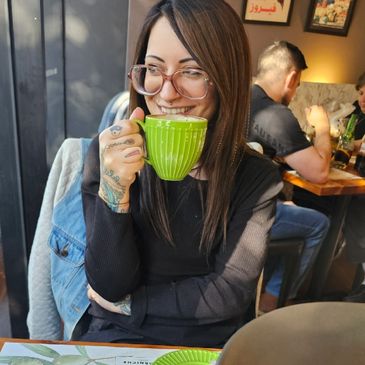 Woman with glasses sipping coffee in a cafe.