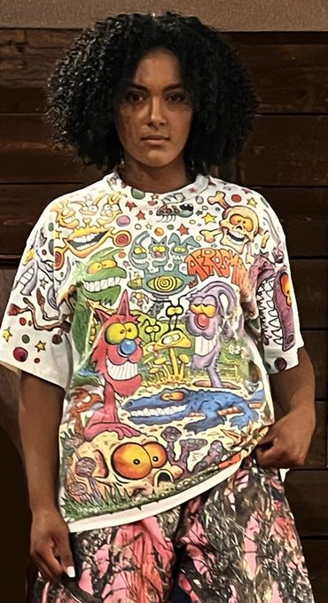 Person wearing a colorful cartoon-themed T-shirt and patterned pants.