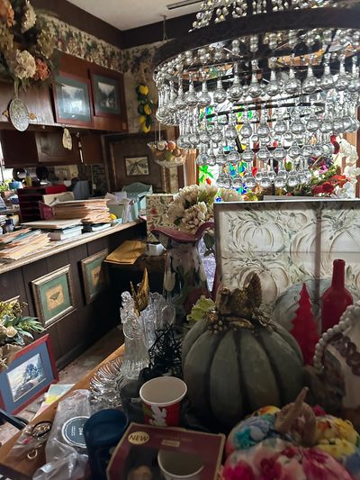 Cluttered vintage room with decorative items and chandelier.