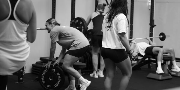 People exercising in a gym with weights and benches.