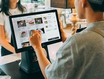 A person browsing a food menu on a touchscreen device at a cafe counter.