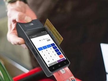 Hand holding a modern card reader with a calculator app displayed.