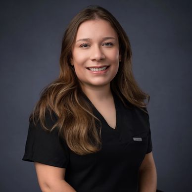 Smiling woman with long hair in a black shirt against a dark background.
