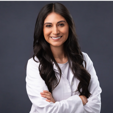 Confident female doctor smiling with arms crossed against gray background.