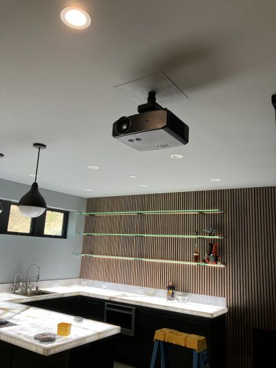 Modern kitchen with ceiling projector and marble countertops.
