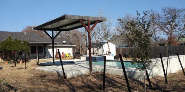 Backyard with a covered pool and bare trees under a clear sky.