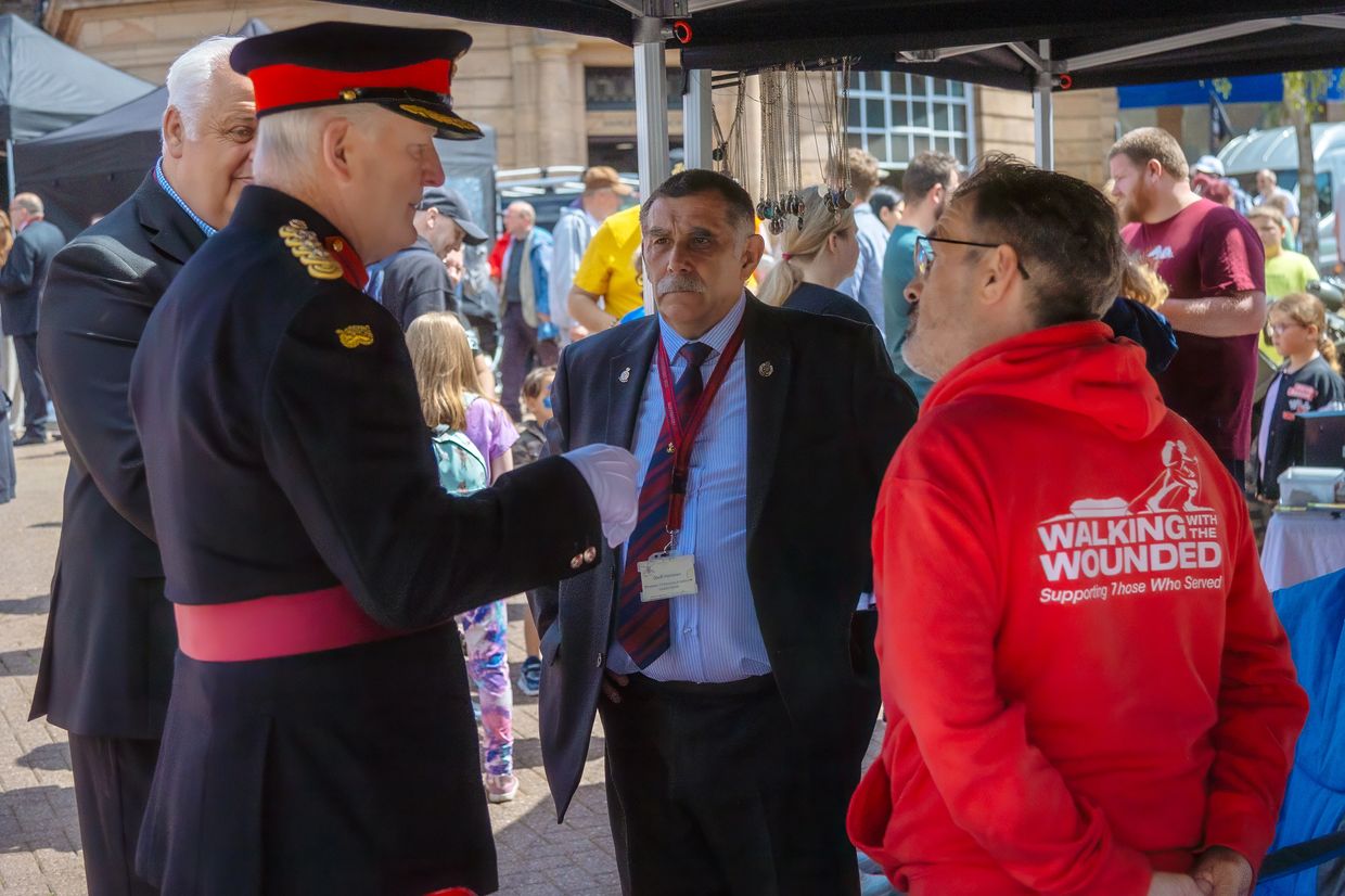 A group of men, including a military officer, engaged in conversation outdoors.