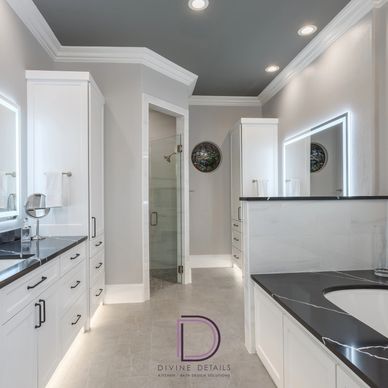 Modern bathroom with white cabinetry and black countertops.