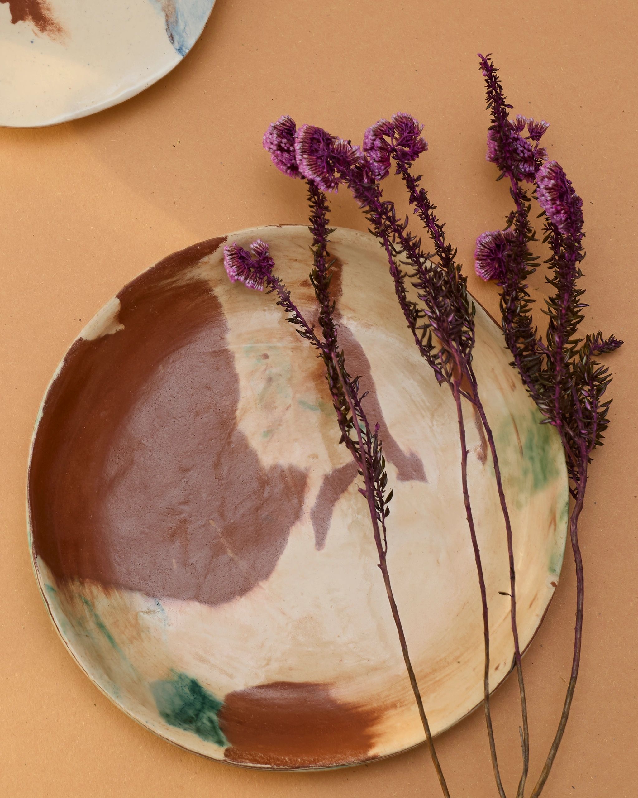 Dried purple flowers on a painted ceramic plate.