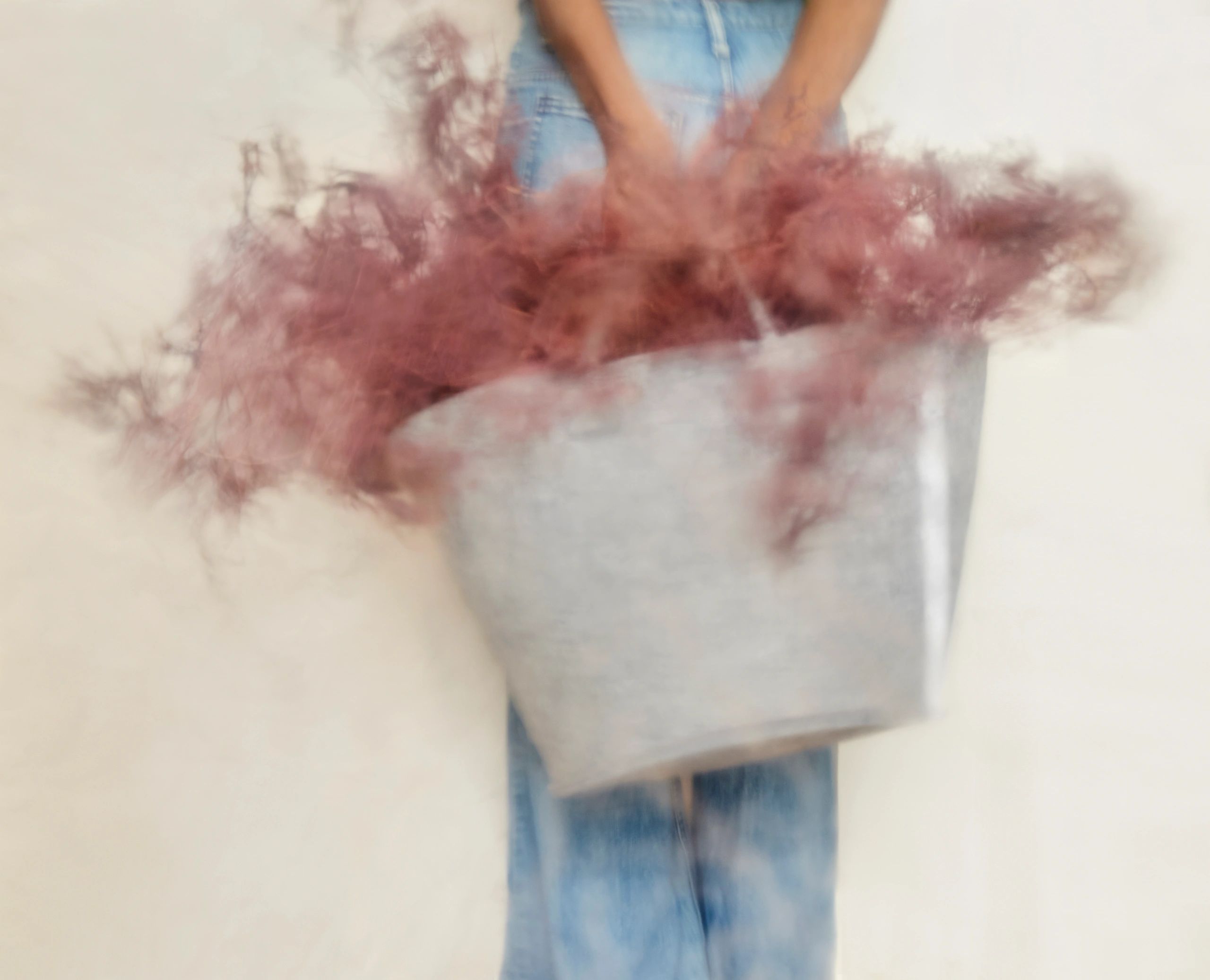 Person shaking red powder from a gray bag.