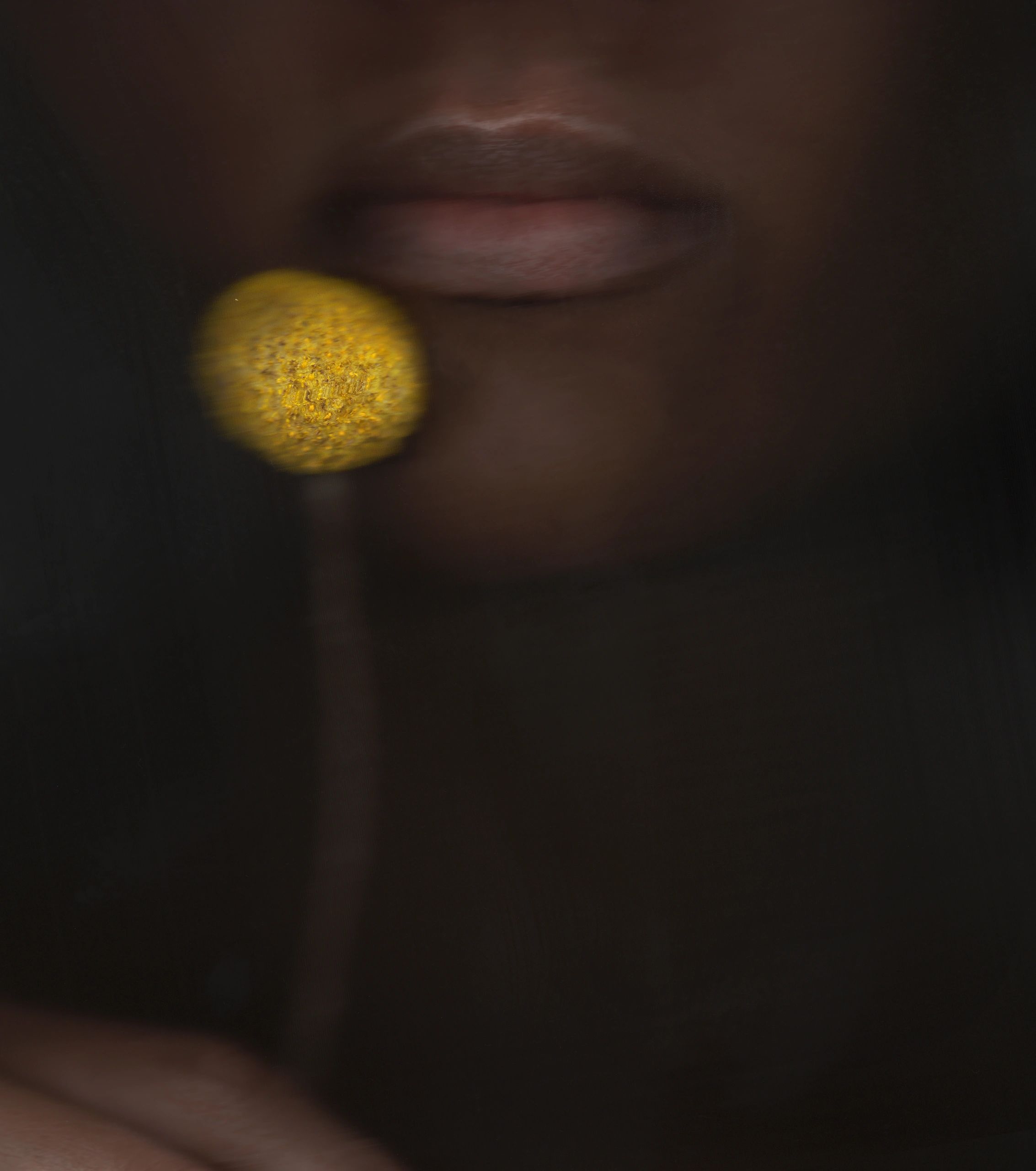 Close-up of lips and a yellow circular object near the mouth.
