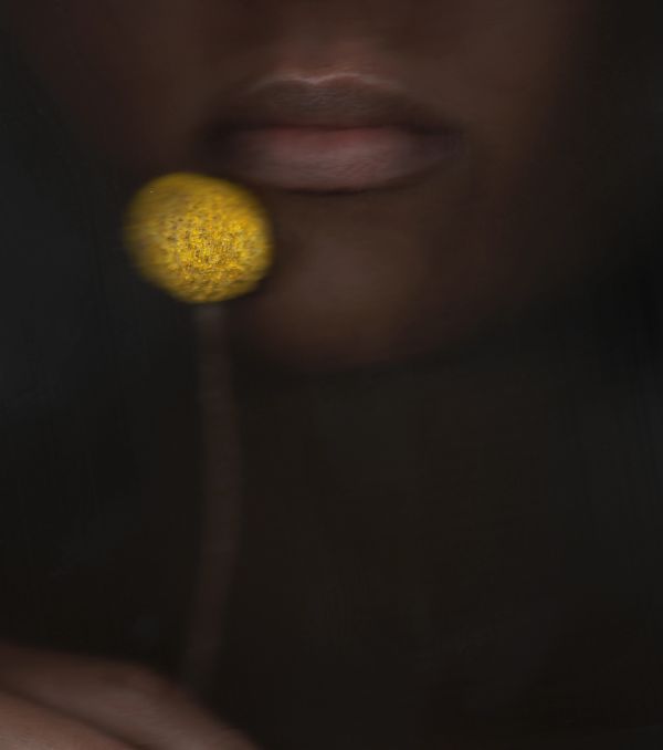 Close-up of lips and a yellow circular object near the mouth.