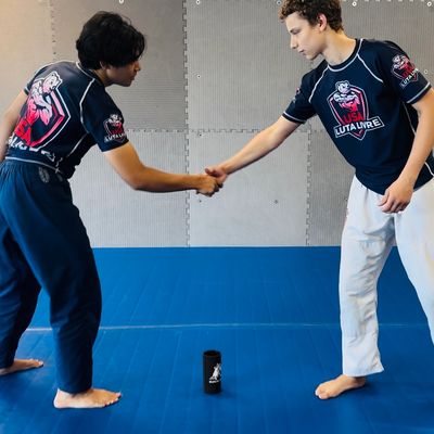 Two boys shaking hands on a martial arts mat.