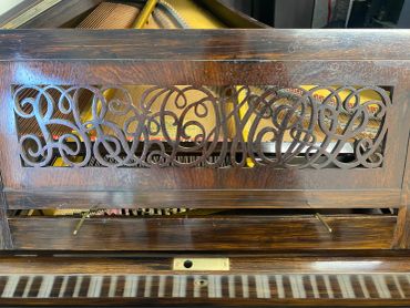 Intricate wooden piano panel with decorative carvings.