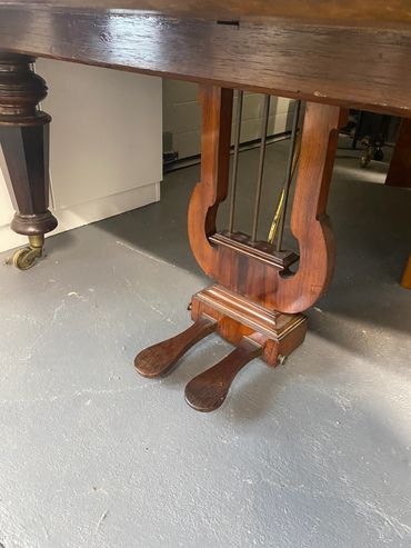 Close-up of piano pedals and wooden base.