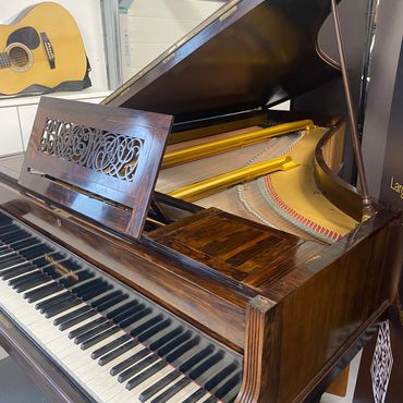 Grand piano with an acoustic guitar in the background.