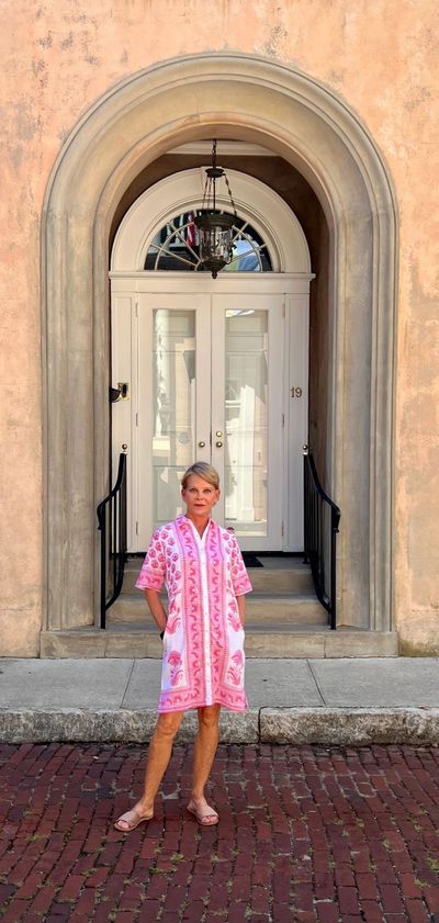 Woman in pink dress standing in front of an arched doorway.