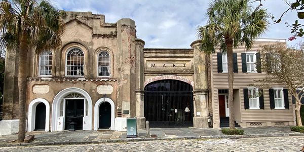 Historic market building with weathered facade and palm trees.