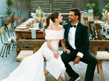 Bride and groom sitting on a bench, smiling at each other after their wedding.