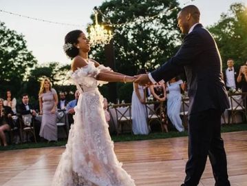 A bride and groom joyfully dancing outdoors at their wedding reception.