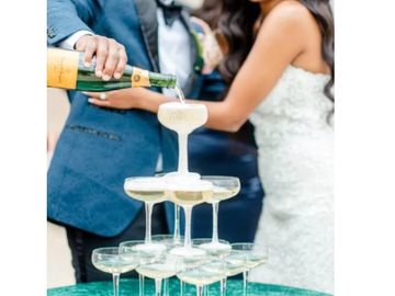 Newlyweds pouring champagne into a glass tower at their wedding.