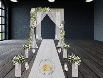 Elegant wedding aisle with floral arch and candles in a modern indoor setting.
