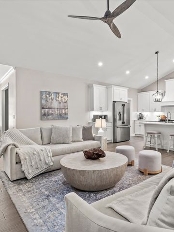 Modern open-concept living room and kitchen with neutral tones and cozy seating.