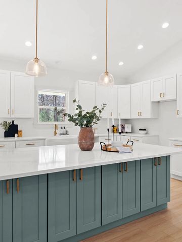 Modern kitchen with blue island and white cabinets.