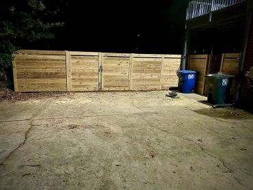 Wooden gate with trash bins at night.