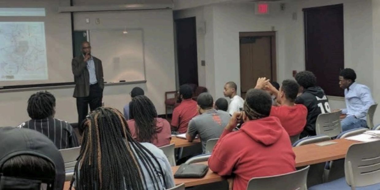 A man giving a lecture to an attentive group of students.