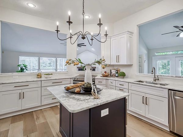 Modern kitchen with white cabinetry and marble island.