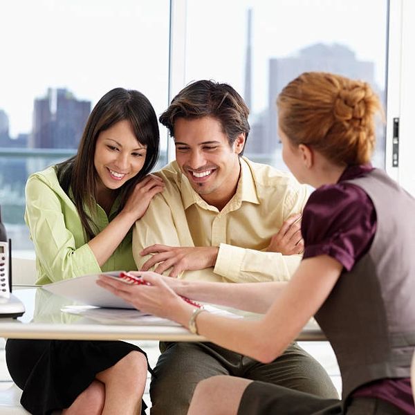 Three professionals discussing paperwork at table.