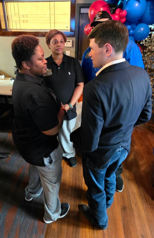 Three people engaged in conversation indoors.