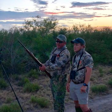 Two hunters in camouflage at sunset.