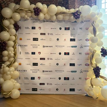 Balloon arch decoration framing a sponsor banner at an event.